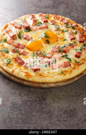 Hot pizza carbonara with bacon, egg, cheese and herbs close-up on a wooden board on the table. Vertical Stock Photo