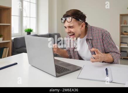 Young man frustrated because of error and data loss shouting at his laptop computer Stock Photo
