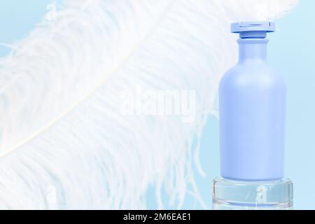 Unbranded blue shampoo, conditioner or shower gel bottle for branding and label on glass podium and large white ostrich feather on blue background. Mo Stock Photo
