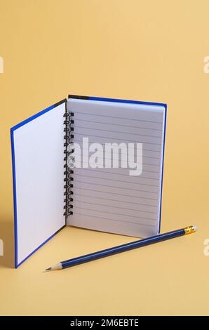 Opened notebook and pencil on yellow background Stock Photo
