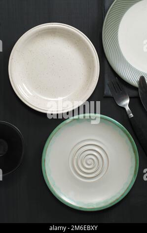 Various empty plates on black wooden table, top view Stock Photo