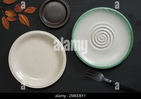Various empty plates on black wooden table, top view Stock Photo