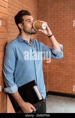 Caucasian businessman drinking coffee from takeout disposable coffee cup Stock Photo