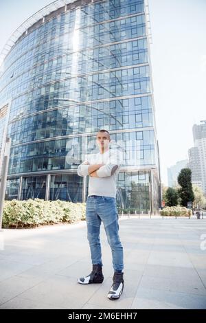 The guy is standing with his hands folded. Young man near the glass house. Leadership people person concept. Stock Photo