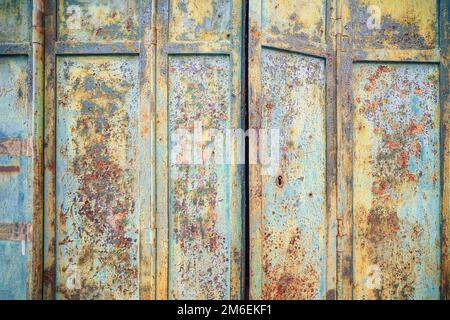 Rusty old metal door with peeling paint in beautiful colors on a grunge background Stock Photo