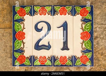 Weathered grunge square faience enameled decorated plate of number of street address with number 21 Stock Photo