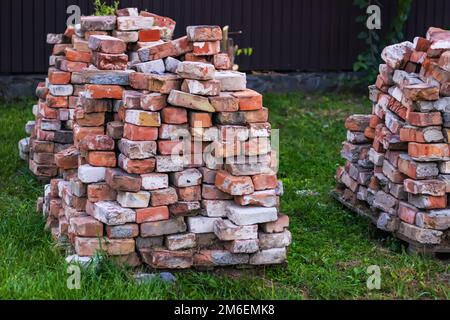 A stack of red clay bricks on a grass. Stock Photo