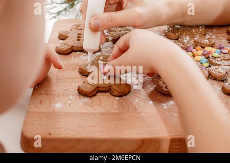 Christmas homemade gingerbread man cookies. Gingerbread Girls and Boys Dough on Wooden Background. Children's hand and gingerbre Stock Photo