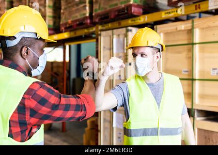 Interracial warehouse worker with face mask do elbow bump greeting Stock Photo