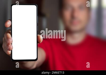 Man demonstrating smartphone with big blank white screen at camera. Man showing copy space for mobile app advertisement. Mockup Stock Photo