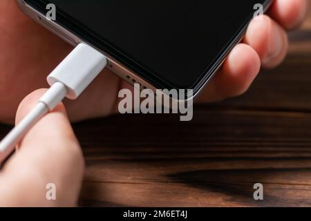 Man hands plugging a charger in a smart phone. Man using smartphone with powerbank. Man charging battery on mobile phone at home Stock Photo