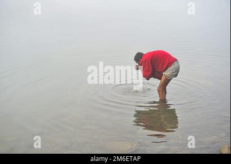 Non Exclusive: 04 January 2023 In Sylhet-Bangladesh: A man is seen wash his face and hand in the Surma River in deep foggy winter morning in Sylhet, B Stock Photo