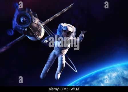 Astronaut waving in outer space against the backdrop of the Soyuz space craft, deep space stars, planet Earth. Space exploring discovery mission Stock Photo