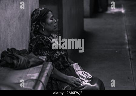 black and white mexican woman doze off at the local market. she was embroidering fabrics. sunlight detail. Stock Photo