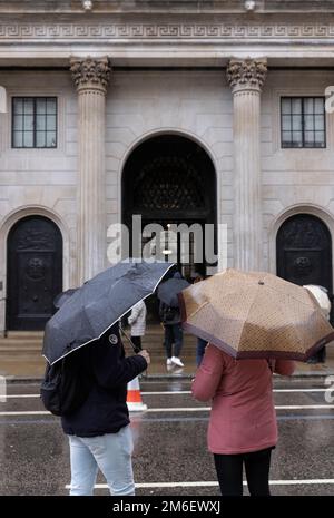 People cover from the winter rain under their umbrellas outside the Bank of England, in the Square Mile, City of London, UK Stock Photo