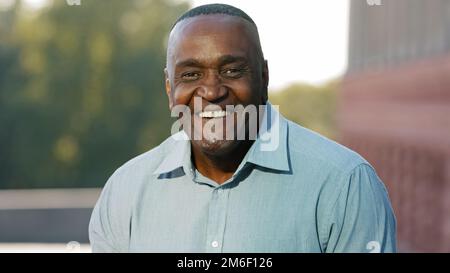 Close up male happy smiling toothy face. Portrait in city outdoors African American mature senior man ethnic middle-aged adult elderly businessman Stock Photo