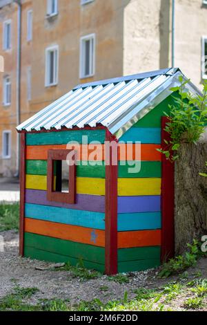 Childrens wooden multi-colored house with a triangular roof stands on an empty playground during the virus and quarantine epidem Stock Photo