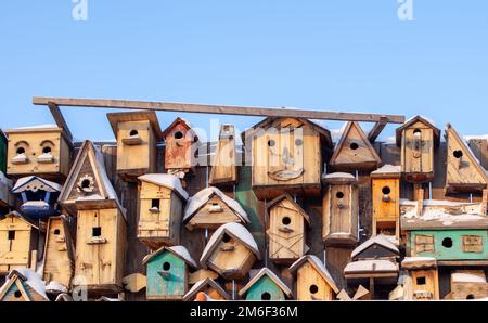 Many different forms of bird feeders.Birdhouses hang on a wooden fence Stock Photo