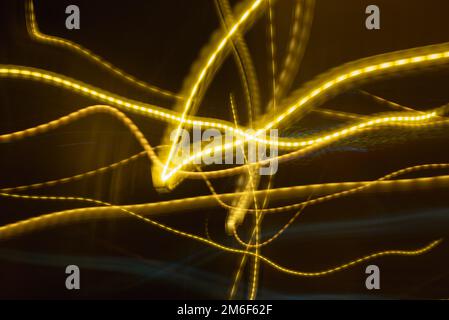 Beautiful colorful background.Long exposure light painting, curvy lines of different color in vibrant neon on black background. Blue,White,Red,Green. Stock Photo