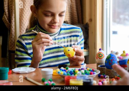 A twelve-year-old girl paints Easter eggs for the holiday Stock Photo