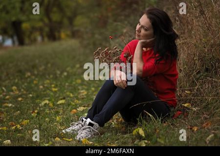 Beautiful thirty year old woman relaxes in the autumn park Stock Photo