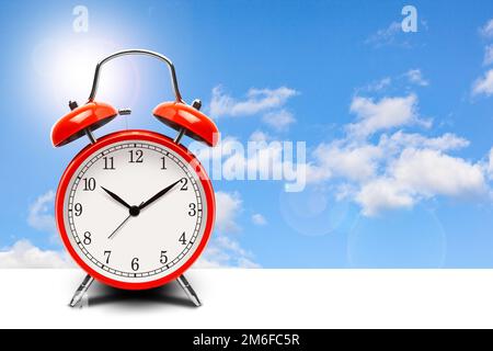 Red alarm clock on blue sky background Stock Photo
