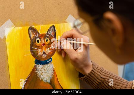 The artist draws with acrylic paints a drawing of a cat on an easel, close-up Stock Photo