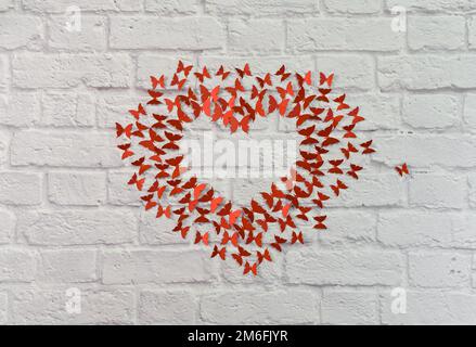 a heart made of butterflies. paper red butterflies on a brick wall background. the concept of love. Stock Photo