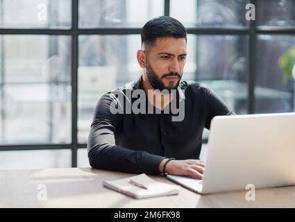 Bearded young businessman working on modern office. Consultant man thinking looking in monitor computer Stock Photo
