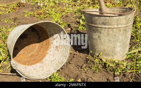 Two old, dirty, rusty, iron buckets with dirty inside and outside are lying on the ground Stock Photo