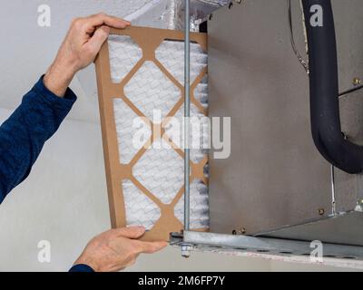 HVAC service technician changing dirty indoor air filter in residential heating and air conditioning system. Home air duct ventilation system maintena Stock Photo