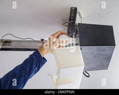 Man replacing light bulb in residential home overhead garage door opener. Stock Photo