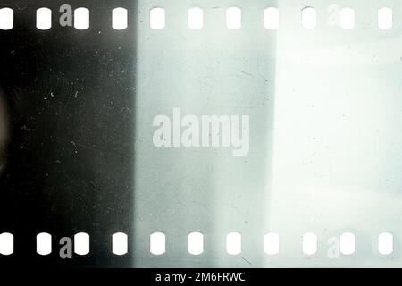 Dusty and grungy 35mm film texture or surface. Perforated scratched camera film isolated on white background. Stock Photo