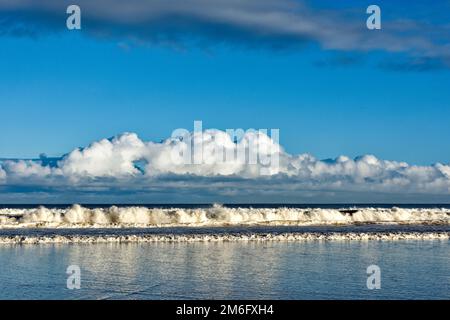 Lossiemouth East Beach Moray coast Scotland blue sky white clouds and surf from a breaking waves in winter Stock Photo