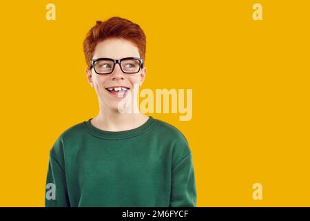Portrait happy smiling red-haired confident boy in transparent glasses with a funny expression looks away. Stock Photo