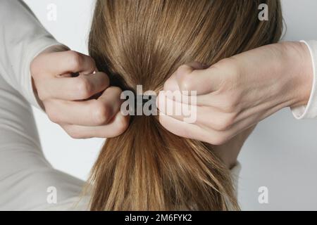 Back view of woman's brown hair tied in a ponytail stock photo