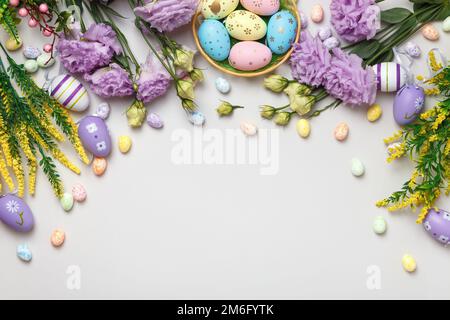 Easter composition. Top view eggs in basket purple yellow flowers on gray background Stock Photo
