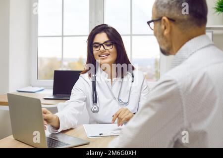Doctor discussing test results and diagnosis to patient using laptop computer Stock Photo