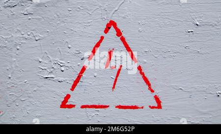 Red electrical hazard sign with lightning in a triangle on a gray painted metal junction box. Stock Photo