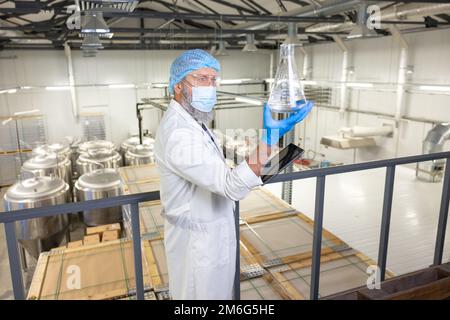 Technologist focused on examining the contents of a glass vessel Stock Photo