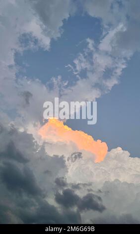 Heart shaped clouds in sky at sunset in italian mountains Stock Photo