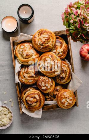Fresh Homemade Rolls Buns with apples and cinnamon in glaze on a table with natural linen tablecloth. Top view flat lay background. Stock Photo
