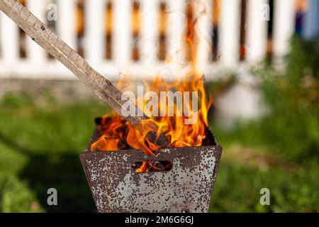 The firewood in the grill burns with a bright orange flame of fire Stock Photo