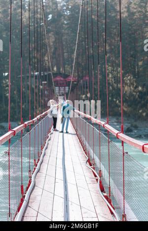 A suspension bridge over a wide river in the mountains. Stock Photo