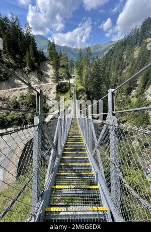 Suspension bridge between the trees in the alps mountains in Kals am Grossglockner Stock Photo