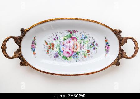 Beautiful Italian porcelain dish decorated with with flowers and gold isolated on white background.  Vintage ashtray with floral decor. Stock Photo