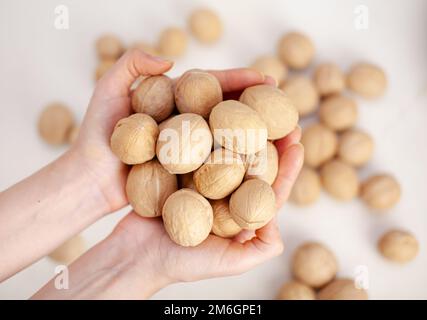 Lots of whole walnuts in women's hands close-up. Healthy, organic food Stock Photo
