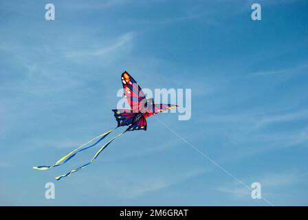Children's butterfly kite flying on blue sky background Stock Photo