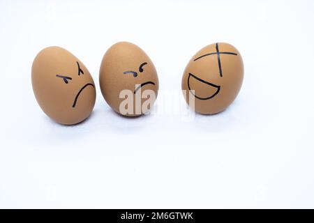 Two angry eggs watching an egg laughing Stock Photo