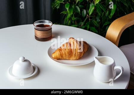 coffee and croissant on a plate on a white table in the living r Stock Photo